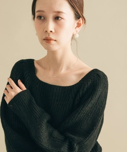 Collana a catena d'argento minimale abbinata a un maglione nero a maglia e perle