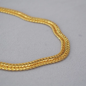 Nahaufnahme einer goldenen Weizenkette mit dichter gewebter Textur und poliertem Finish