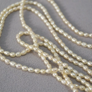 Vue macro de perles d'eau douce naturelles en forme de riz sur un tissu gris doux
