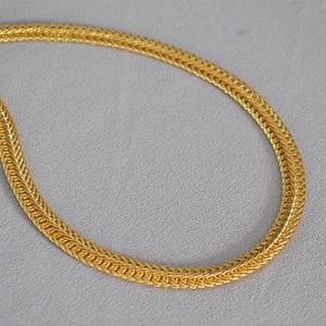 Makroaufnahme einer hochpräzisen goldenen geflochtenen Halskette mit metallischer Textur