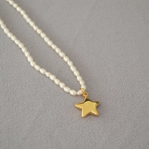 Detailed close-up of freshwater pearl necklace with polished gold star pendant detail