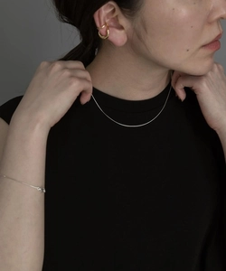Dettaglio della collana a catena serpente minimalista e dei polsini dorati su una modella