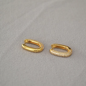 Close-up of golden U-shaped hoop earrings with three rows of micro-pave white zircons