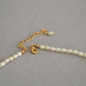 Gros plan d'un collier en perles d'eau douce avec fermoir mousqueton doré et chaîne