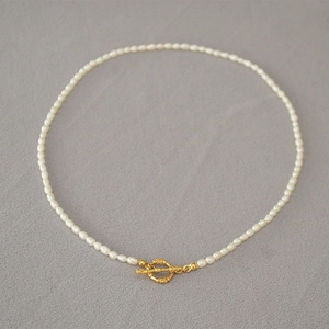 Détail du collier de perles blanches avec fermoir à bascule doré au design vintage