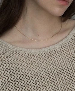 Dettaglio della sottile collana a catena serpente dorata minimalista indossata sulla clavicola