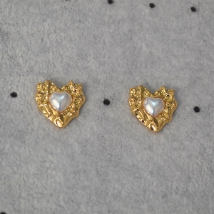 Detail of vintage irregular heart earrings with golden hammered texture and shell inlay