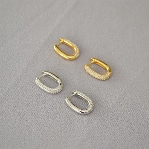 Close-up of gold and silver U-shaped hoop earrings with micro-pave sparkling zircon stones