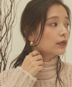 Close-up of elegant gold ball earrings and layered rings on a female model