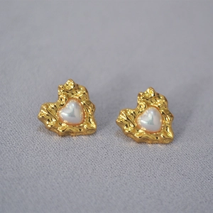 Macro view of vintage heart earrings with hammered gold texture and shell inlay detail