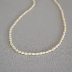 Détail macro de perles d'eau douce blanches naturelles avec éclat doux sur tissu gris