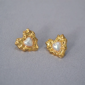 Macro detail of gold hammered heart earrings with shell inlay and liquid metal texture