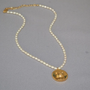 Detail of freshwater pearl necklace featuring a cat head gold coin pendant and lobster clasp