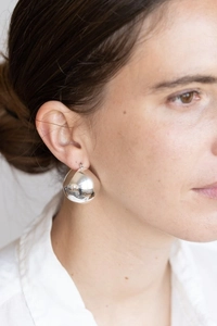 Close-up of a large oversized silver hollow ball earring with a mirror finish on a model