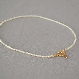 Détail d'un collier de perles élégant avec fermoir à bascule OT doré sur tissu doux