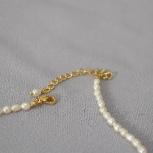 Collier minimaliste en perles d'eau douce avec fermoir doré ajustable sur tissu gris
