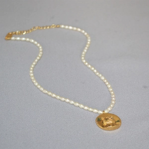 Detail of freshwater pearl necklace with a gold cat coin pendant and adjustable lobster clasp