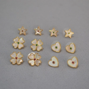 Détail de boucles d'oreilles trèfle, cœur et étoile plaquées or avec nacre naturelle