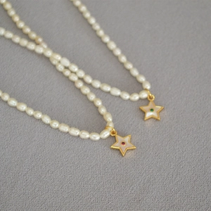Detail of freshwater pearl necklace with star pendant featuring red and green zircons