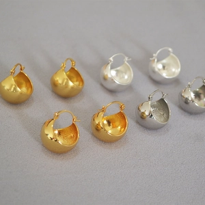 Detailed view of chunky hollow ball hoop earrings in polished gold and silver plating