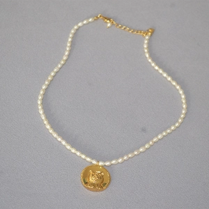 Detail of freshwater rice pearls with a golden cat coin pendant and lobster clasp