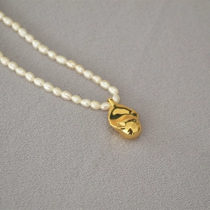 Detail of freshwater pearl necklace with polished gold irregular coin pendant charm