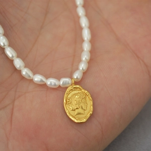 Close-up of a French vintage coin pendant with freshwater pearls held in hand