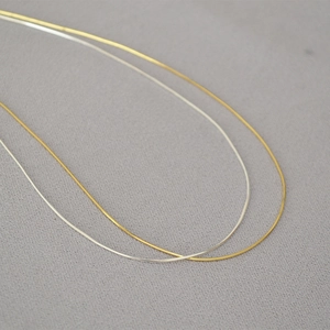 Dettaglio di collane a catena a serpente color oro e argento con finitura lucida