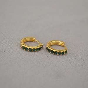 Detailed close-up of gold-plated huggie earrings with inset dark green zircon stones