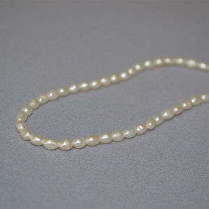 Gros plan de perles d'eau douce en forme de grain de riz sur un collier minimaliste