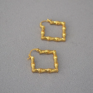 Macro detail of gold-plated square earrings with a bamboo-inspired textured finish