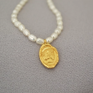 Detail of French vintage necklace with freshwater pearls and gold coin queen pendant