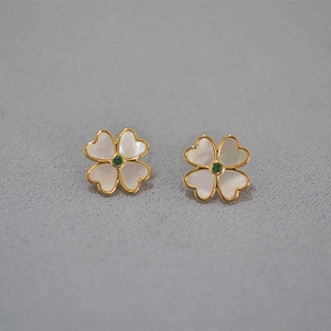 Détail de boucles d'oreilles trèfle avec pétales en nacre blanche et zircon vert central
