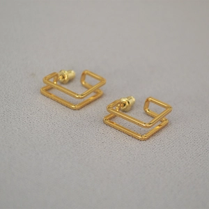 Detailed top view of gold-plated square frame earrings on a grey textured background