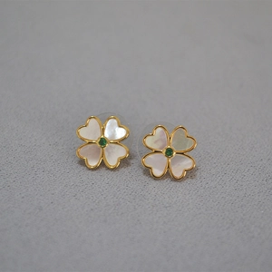 Détail de boucles d'oreilles trèfle en nacre blanche avec une pierre verte centrale