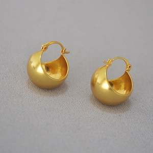 Macro view of chunky golden hollow ball earrings showing high-gloss mirror finish