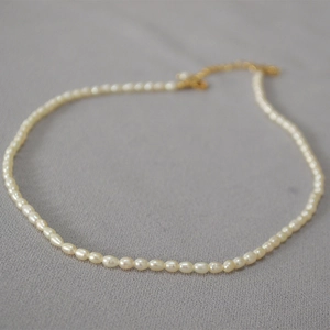 Gros plan d'un collier de perles d'eau douce avec fermoir mousqueton doré et extension