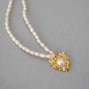 Detail of vintage irregular heart pendant with lava texture and freshwater pearls