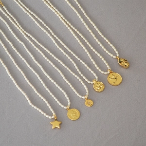 Close-up of freshwater pearl necklaces with vintage gold coin and star pendants
