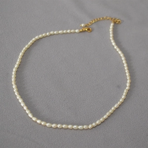 Détail d'un collier de perles d'eau douce avec fermoir mousqueton doré et extension