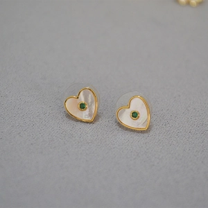 Détail de boucles d'oreilles cœur en or avec nacre irisée et pierre précieuse verte