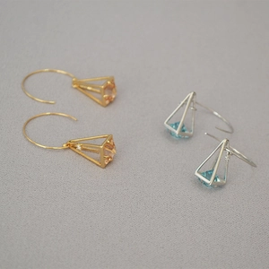 Macro detail of geometric cage earrings with champagne and blue inlaid zircons