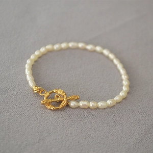 Détail du fermoir OT doré avec texture bambou sur un collier de perles de riz élégant