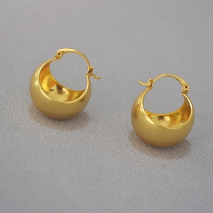 Macro detail of gold-plated hollow ball earrings with a refined matte texture finish