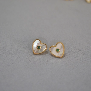 Détail de boucles d'oreilles cœur en nacre blanche avec une pierre centrale verte