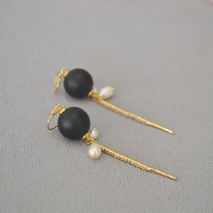 Close-up of baroque earrings with black beads, pearls and sparkling tassel sticks