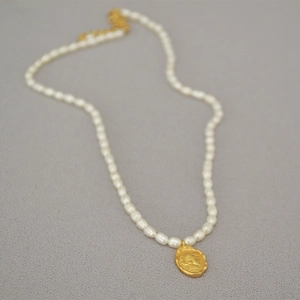 Close-up of freshwater pearl necklace featuring a vintage gold coin pendant with relief