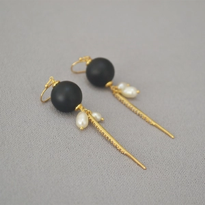 Detail of baroque pearl earrings with black beads and sparkling rhinestone tassels