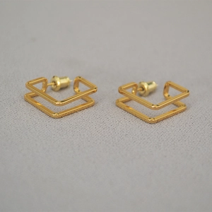 Detail view of gold square hollow geometric earrings with a double-layered line design