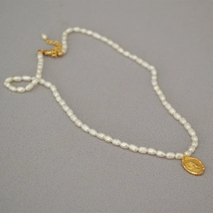 Detail of freshwater pearl necklace with vintage gold coin pendant featuring relief art